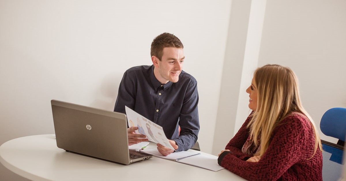 Adult male and female learning by the computer in a classroom